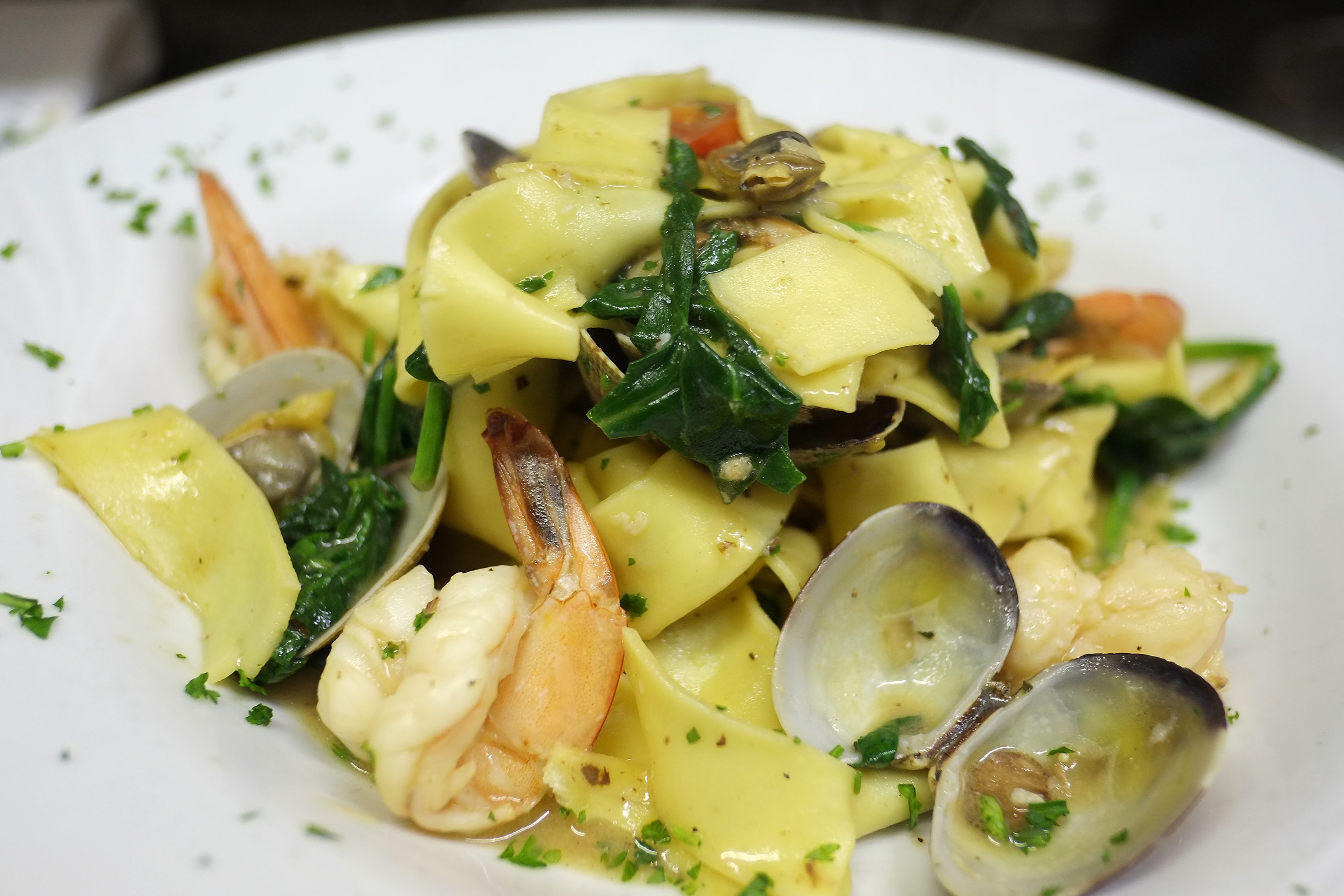 Wide pasta with shrimp, clams, mussels and greens